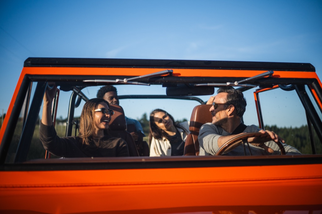 Four friends inside a restored orange vintage Ford Bronco seen through the windshield, photographed for Kindred by Dawn Heumann, photographed by Dawn Heumann