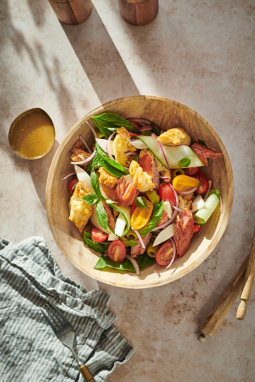 Wooden bowl of smoked salmon panzanella with cherry tomatoes, cucumber, mint, and torn croutons in hard sunlight, photographed in Alaska