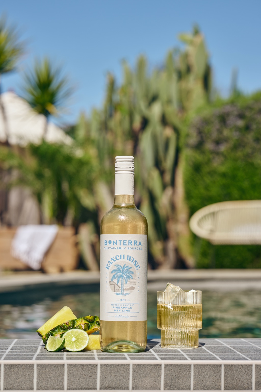 Bonterra Ranch Wine Pineapple Key Lime bottle poolside with pineapple wedges, lime halves, and an iced ribbed glass