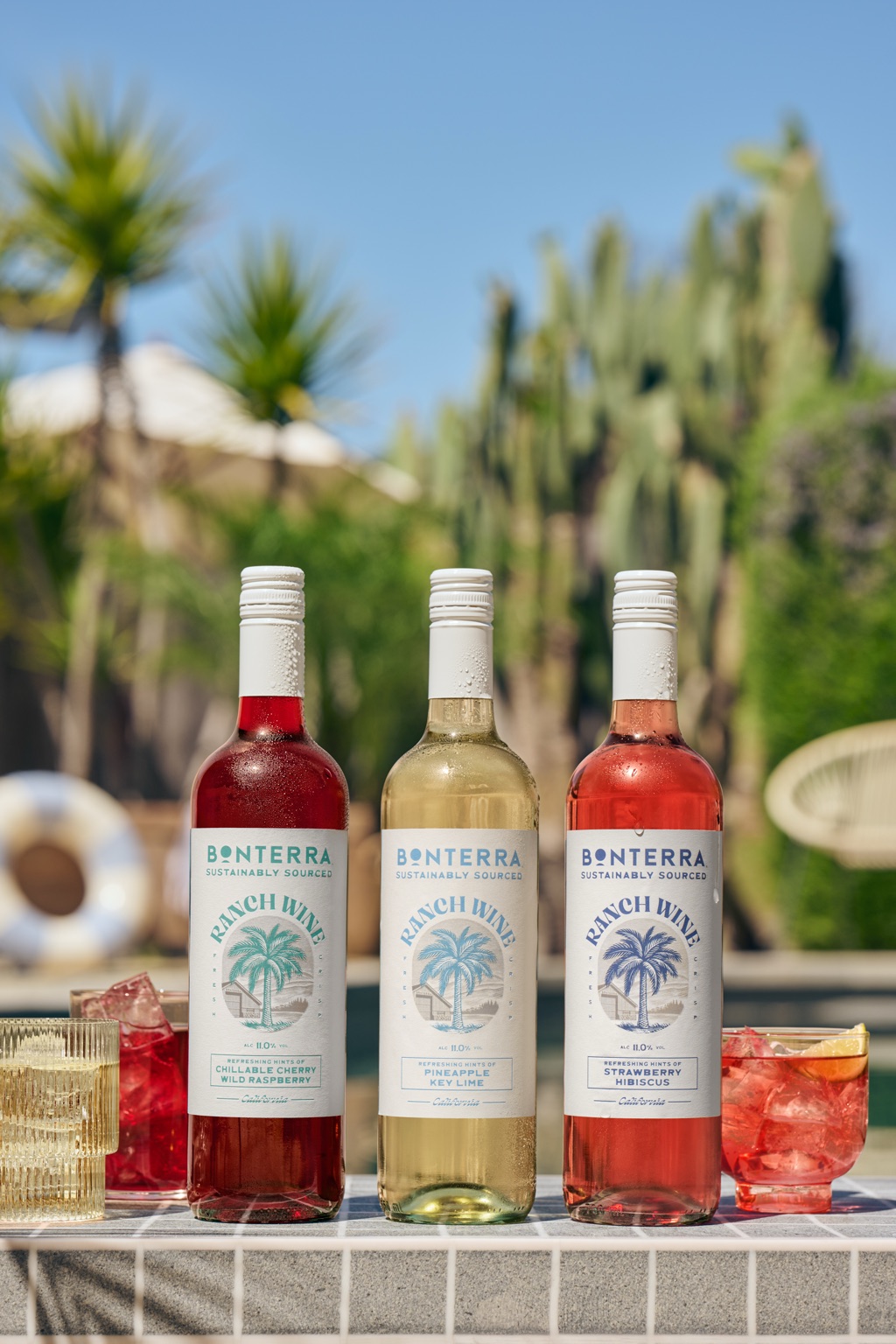 Three Bonterra Ranch Wine flavors lined up poolside, Chillable Cherry Wild Raspberry, Pineapple Key Lime, and Strawberry Hibiscus, with iced glasses