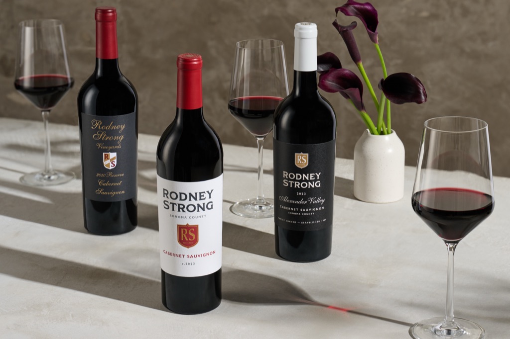 Three Rodney Strong cabernet sauvignon bottles with plum calla lilies in a white vase