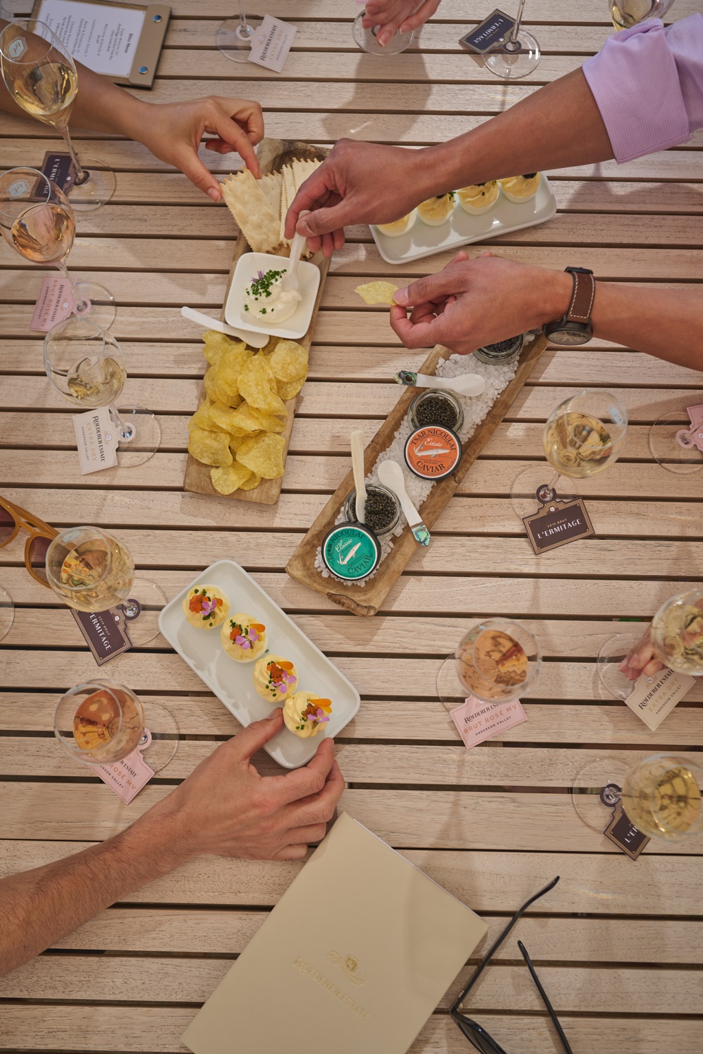Overhead view of a sparkling wine and caviar tasting with deviled eggs, potato chips, and creme fraiche