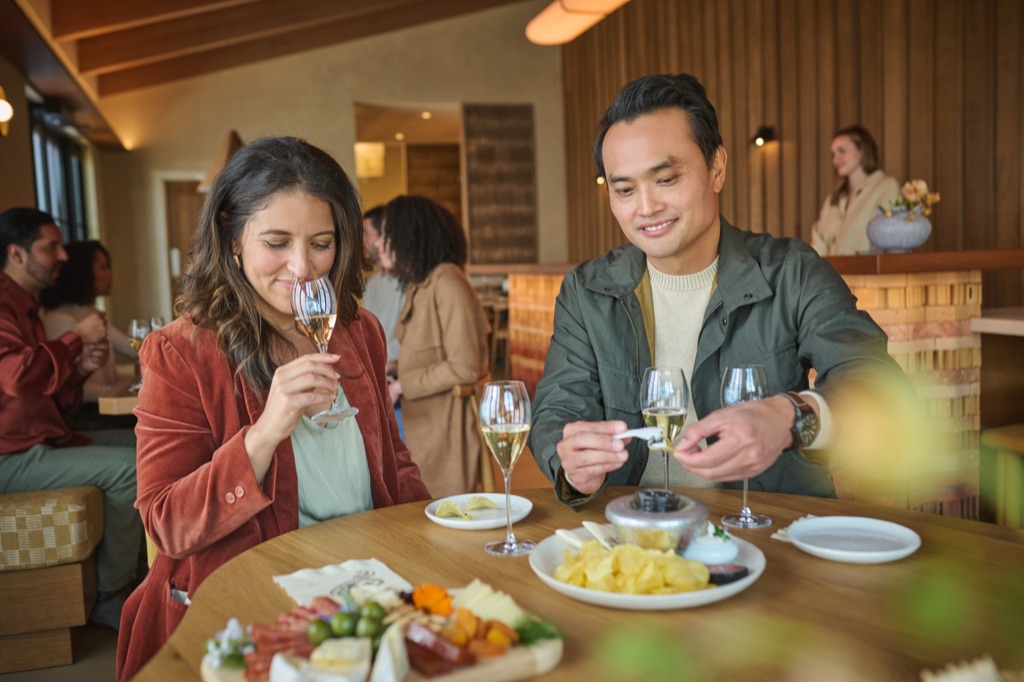 Couple enjoying a sparkling tasting flight with a charcuterie board and caviar service in the tasting room