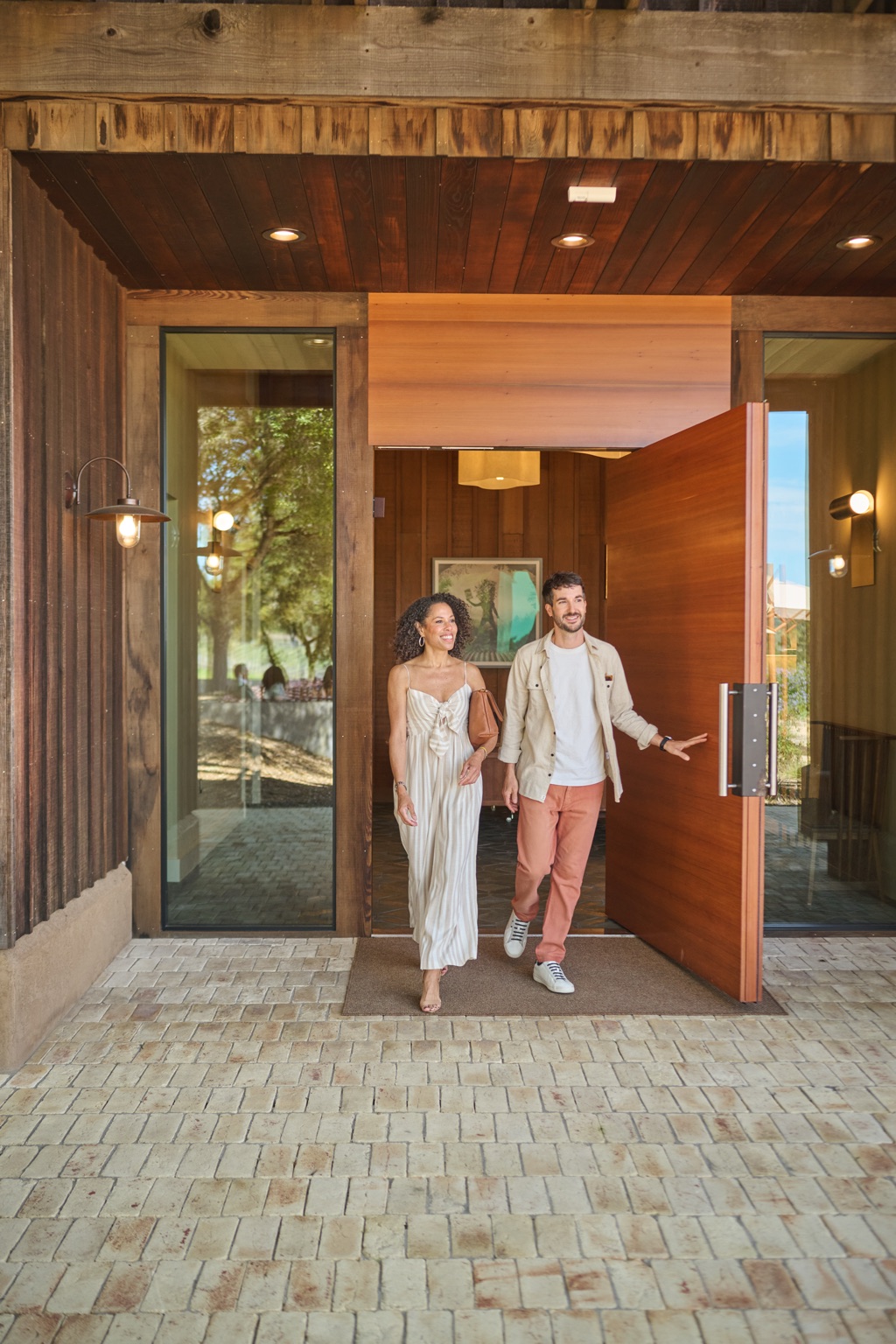 Smiling couple walking out of the Roederer Estate tasting room through a wooden pivot door
