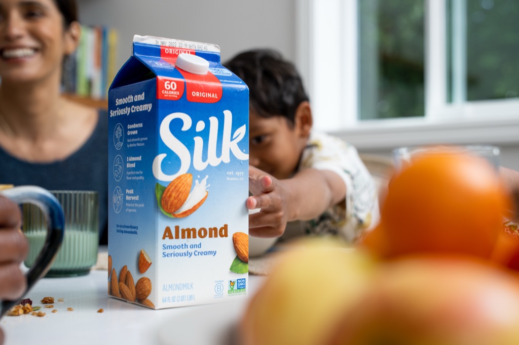 Silk Almondmilk carton heroed on the counter as a boy reaches across the table, campaign photography by Dawn Heumann