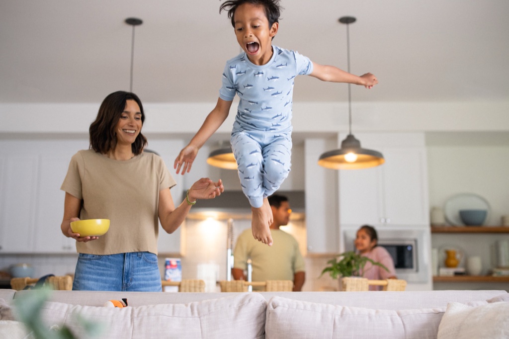 Boy in shark pajamas leaping off the couch while mom laughs, Silk almondmilk campaign photography by Dawn Heumann, photographed by Dawn Heumann