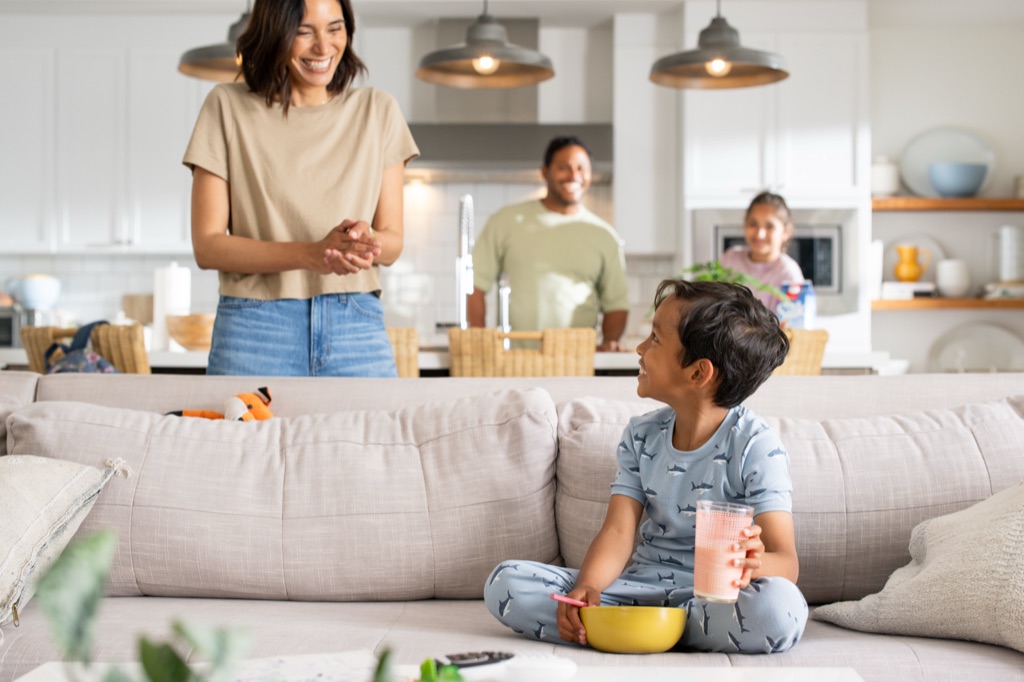 Boy with a smoothie and cereal bowl on the couch while the family starts the morning, Silk campaign photography by Dawn Heumann