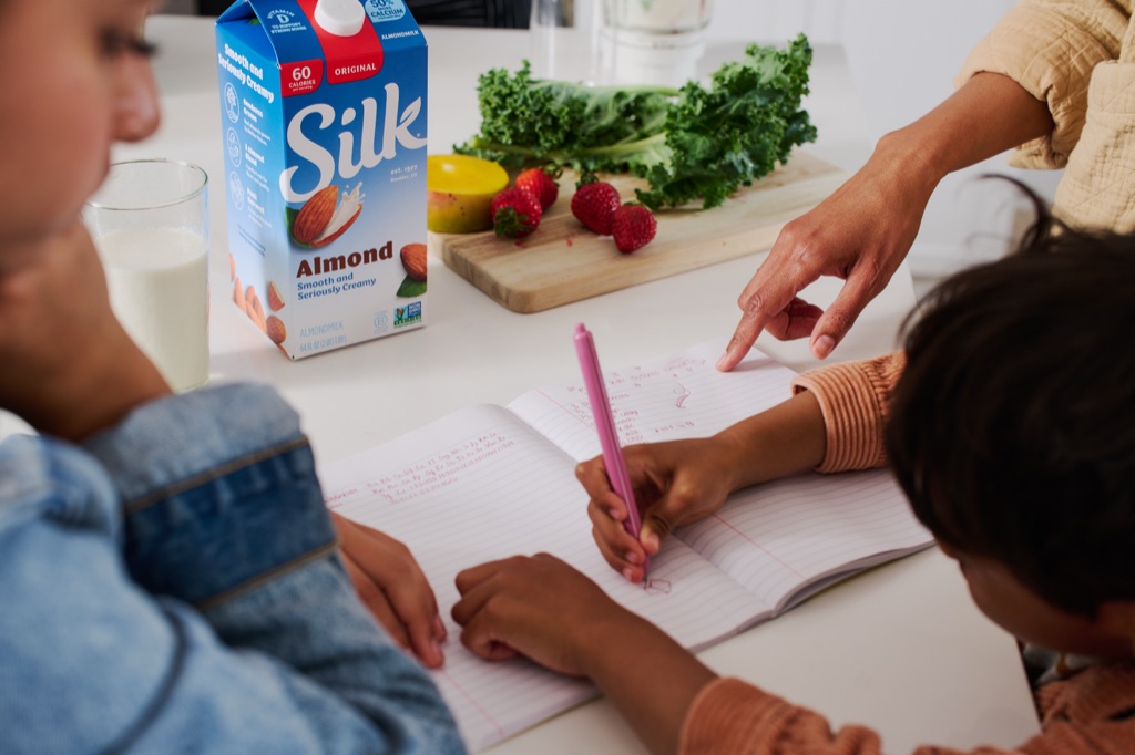 Kids writing a smoothie recipe next to Silk almondmilk, kale, and strawberries