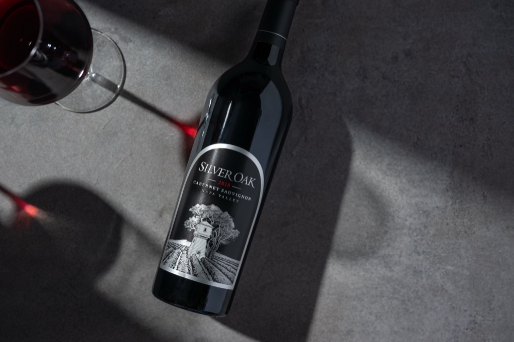 Silver Oak 2018 Napa Valley Cabernet Sauvignon overhead on gray concrete with a glass casting red light