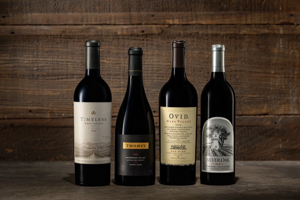 Timeless Napa Valley, Twomey Pinot Noir, OVID Napa Valley, and Silver Oak Alexander Valley bottles against barnwood