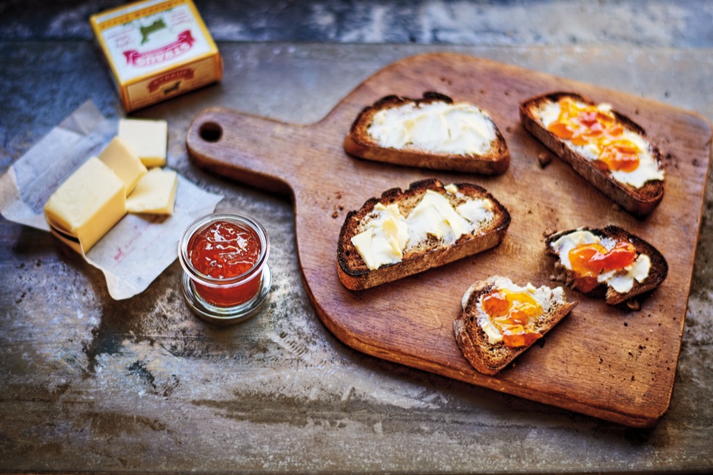 Straus butter on a wooden cutting board with toasts and apricot jam