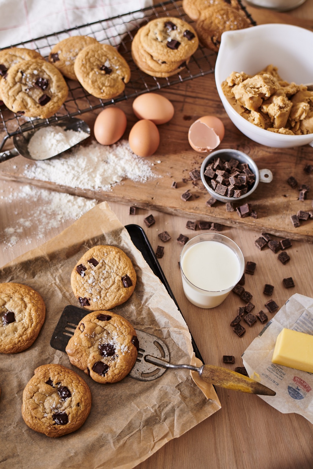 Overhead of salted chocolate chunk cookies with a glass of milk and Straus butter