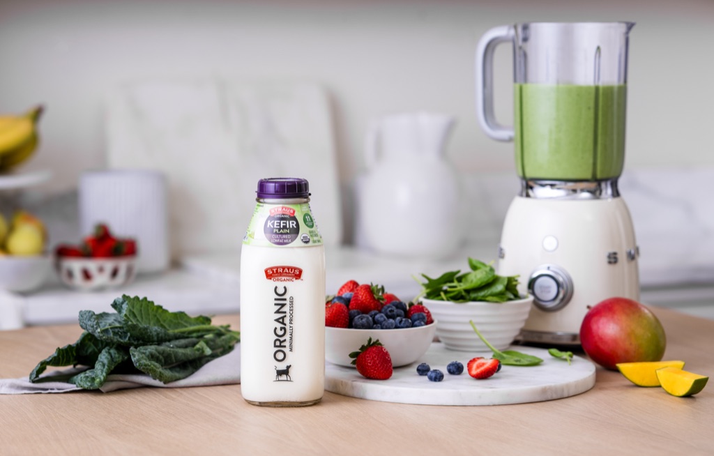 Straus Organic Plain Kefir bottle with kale, berries, spinach, and mango beside a blender of green smoothie
