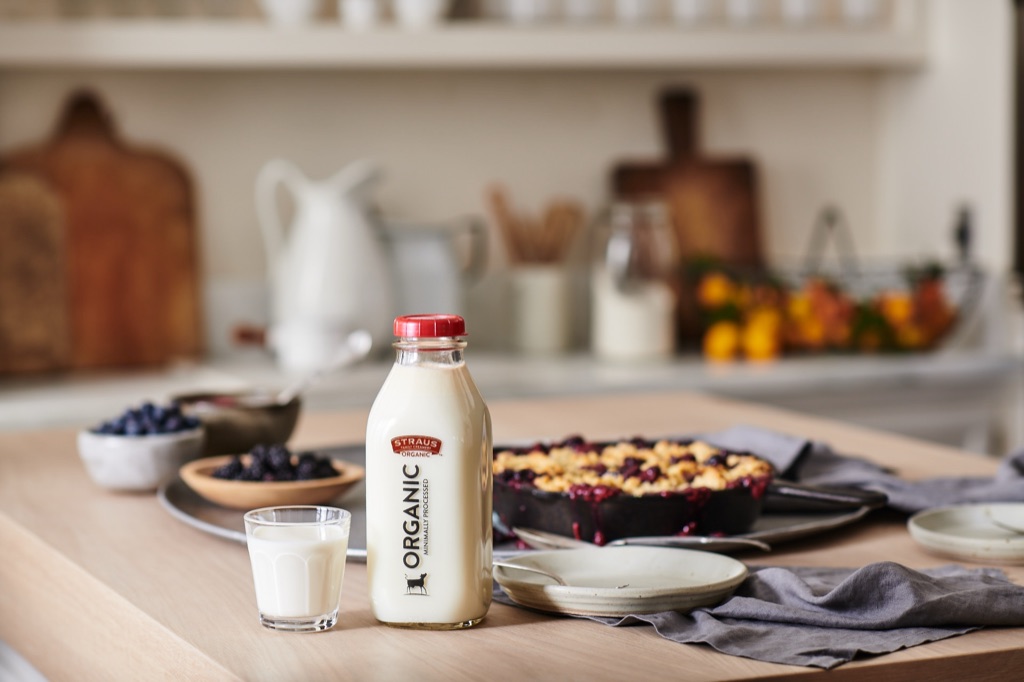 Straus Organic milk bottle and a glass of milk with a berry crumble in a cast iron skillet