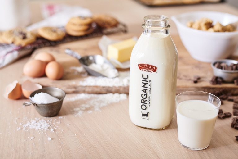 Open bottle of Straus Organic milk with a poured glass in a chocolate chip cookie baking scene, photographed by Dawn Heumann
