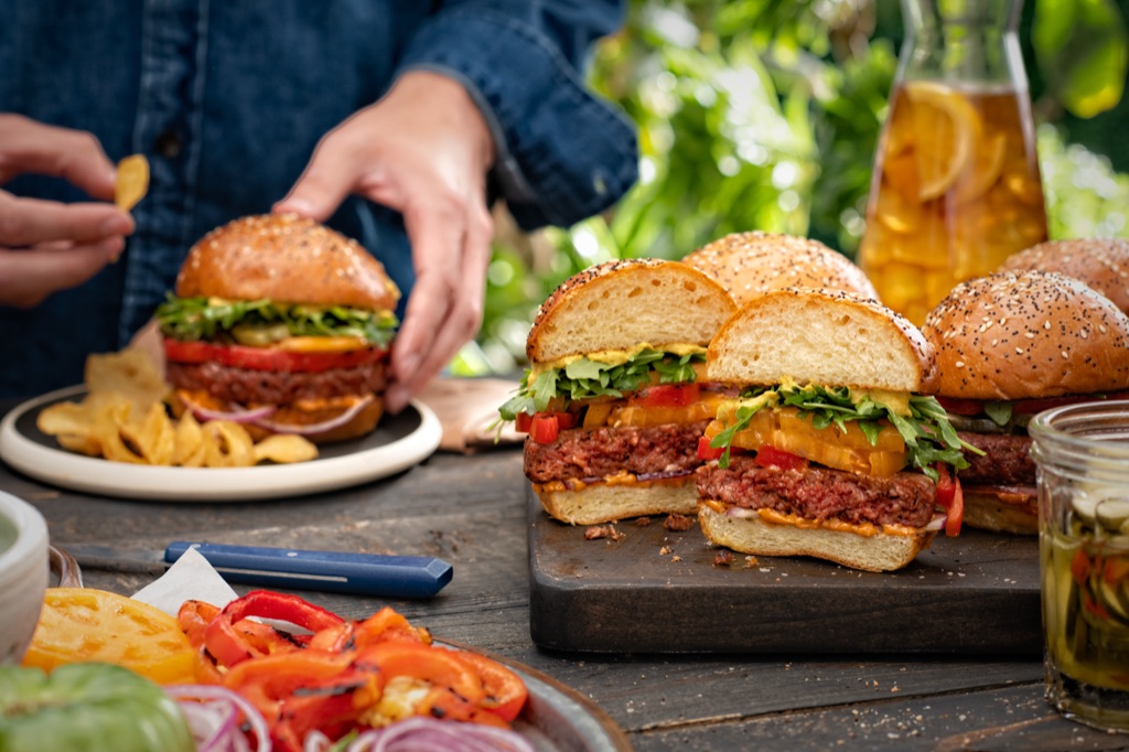 Halved Sweet Earth Awesome Burgers showing the plant-based patty on a cutting board with iced tea