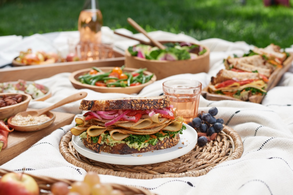 Stacked picnic sandwich made with Sweet Earth plant-based deli slices, pickled onion, and kale pesto on seeded bread