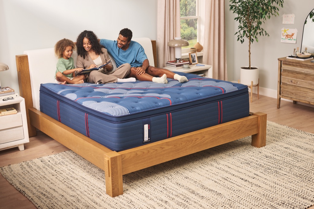 Parents reading a picture book with their child on a Sealy Posturepedic Elite pillow-top mattress
