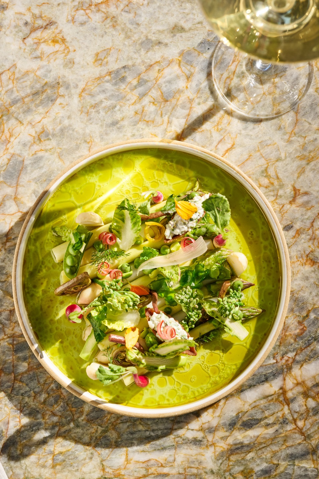Spring vegetables in a bright green broth, photographed from above