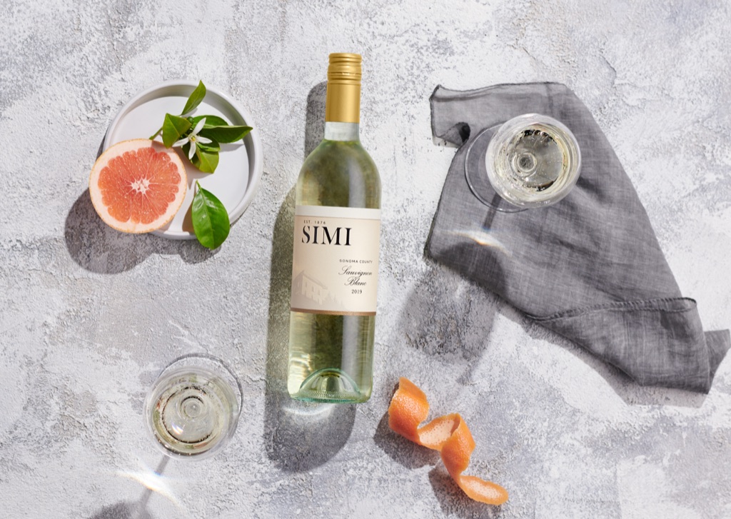 Overhead flatlay of SIMI sauvignon blanc with grapefruit, orange blossom and linen on plaster
