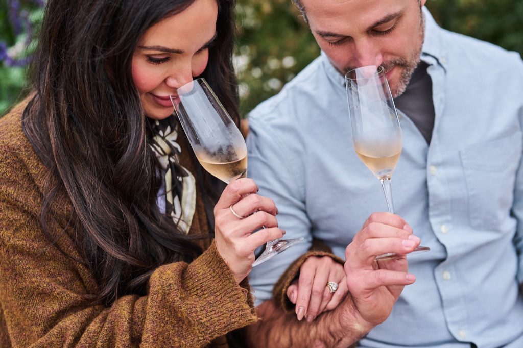 Couple nosing flutes of sparkling wine close-up in a winery garden