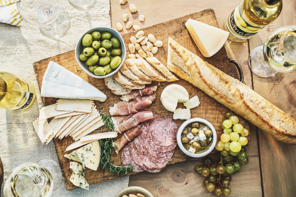 Overhead charcuterie board with white wine on a wood table