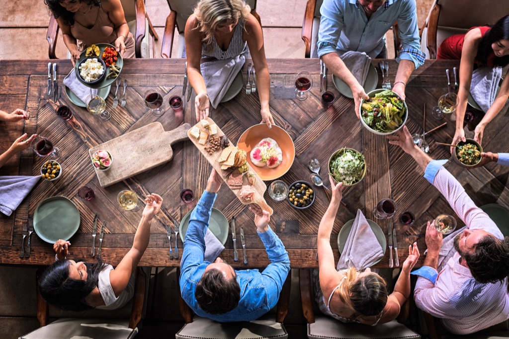 Overhead of a farm table dinner with platters passing hand to hand