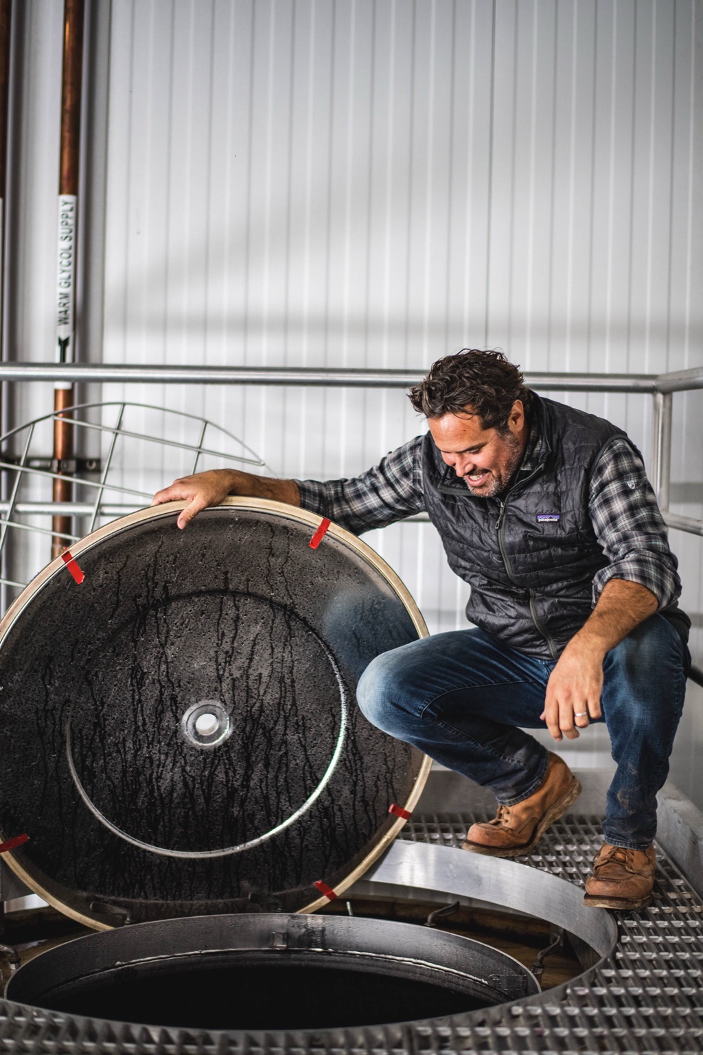 Winemaker checking an open-top fermenter in the cellar