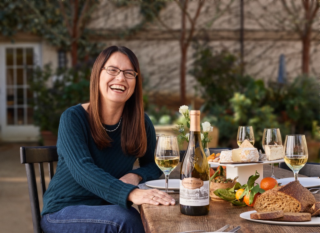 Winemaker laughing at a garden table with her chardonnay