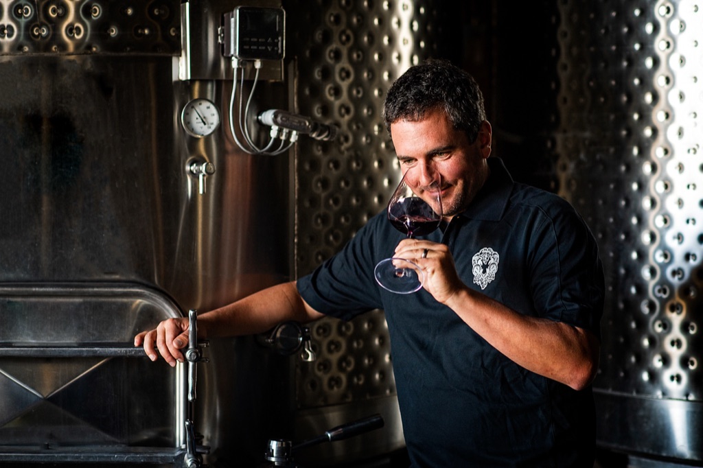 Winemaker tasting red wine beside the stainless tanks