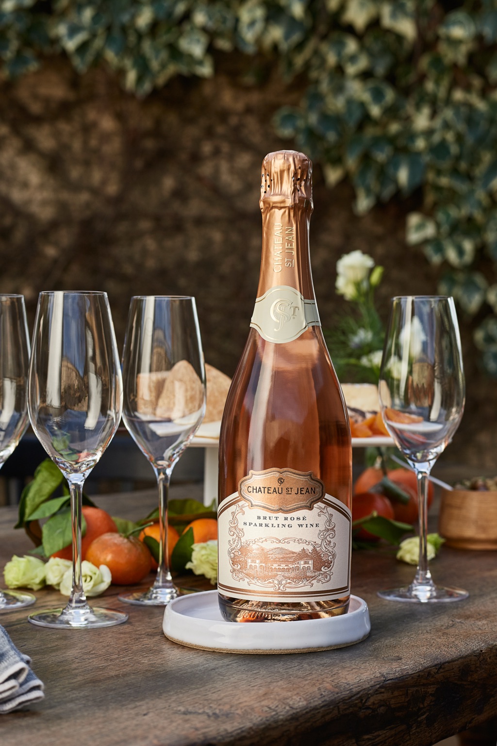Chateau St Jean brut rose sparkling wine with flutes, mandarins, and ivy