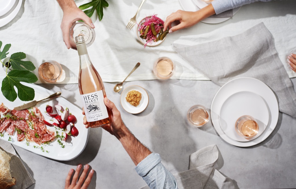 Overhead of a Hess Select pinot gris being poured at a gathered table with charcuterie and figs, photographed by Dawn Heumann