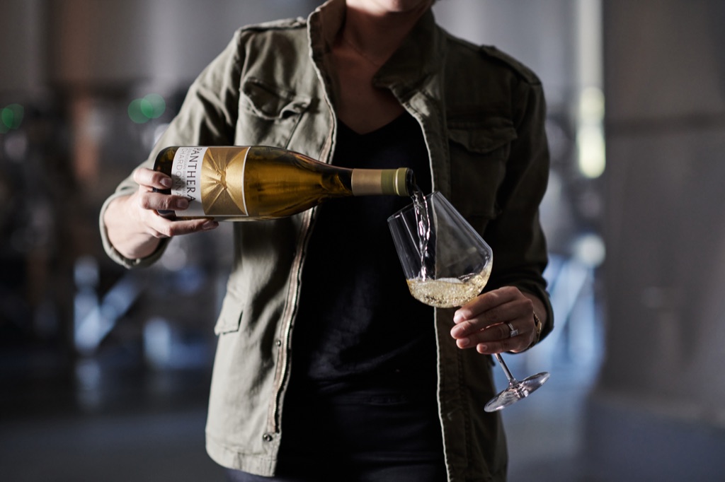 Woman pouring Panthera Russian River Valley chardonnay among stainless tanks in the winery