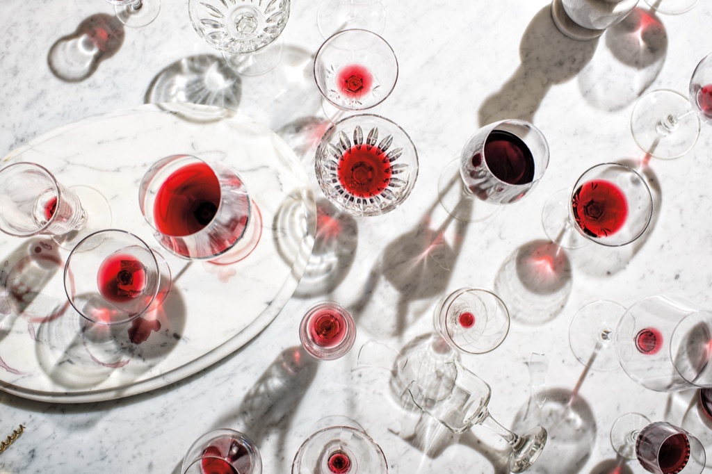 Overhead still life of red wine glasses casting shadows across white marble