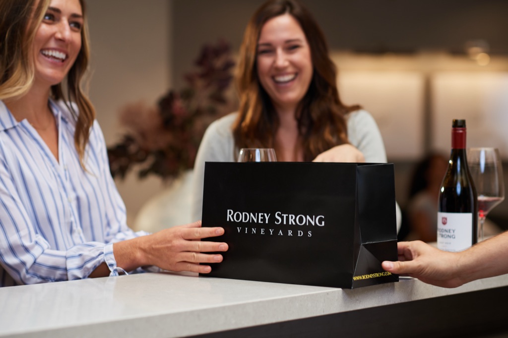 Two women receiving a Rodney Strong Vineyards gift bag at the tasting room counter
