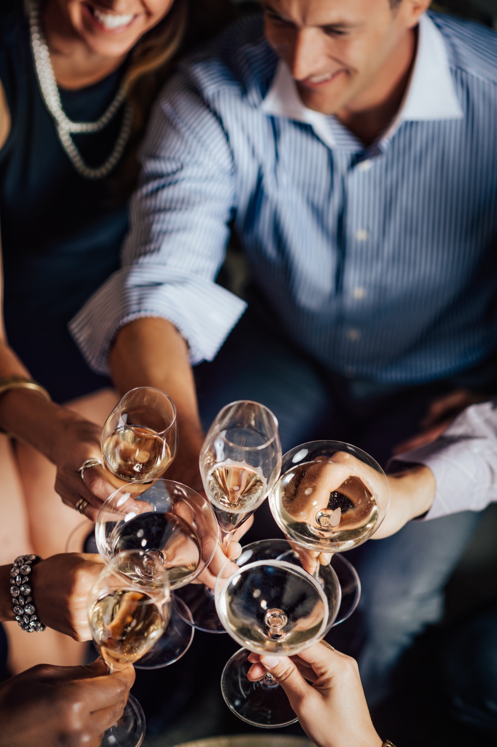 Friends raising mixed coupes and flutes of sparkling wine, seen from above